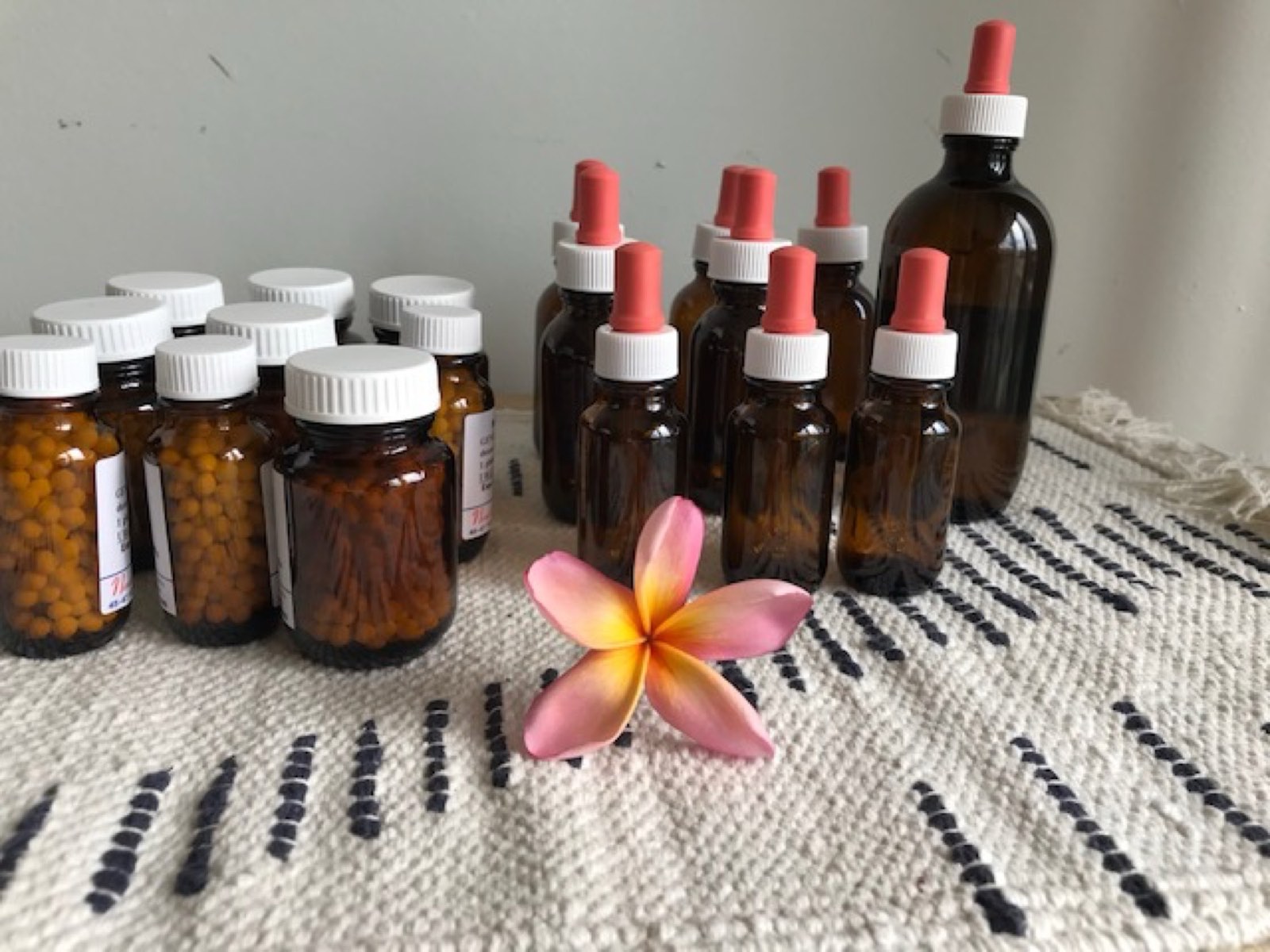 Homeopathic remedy bottles laid out with a frangipani flower